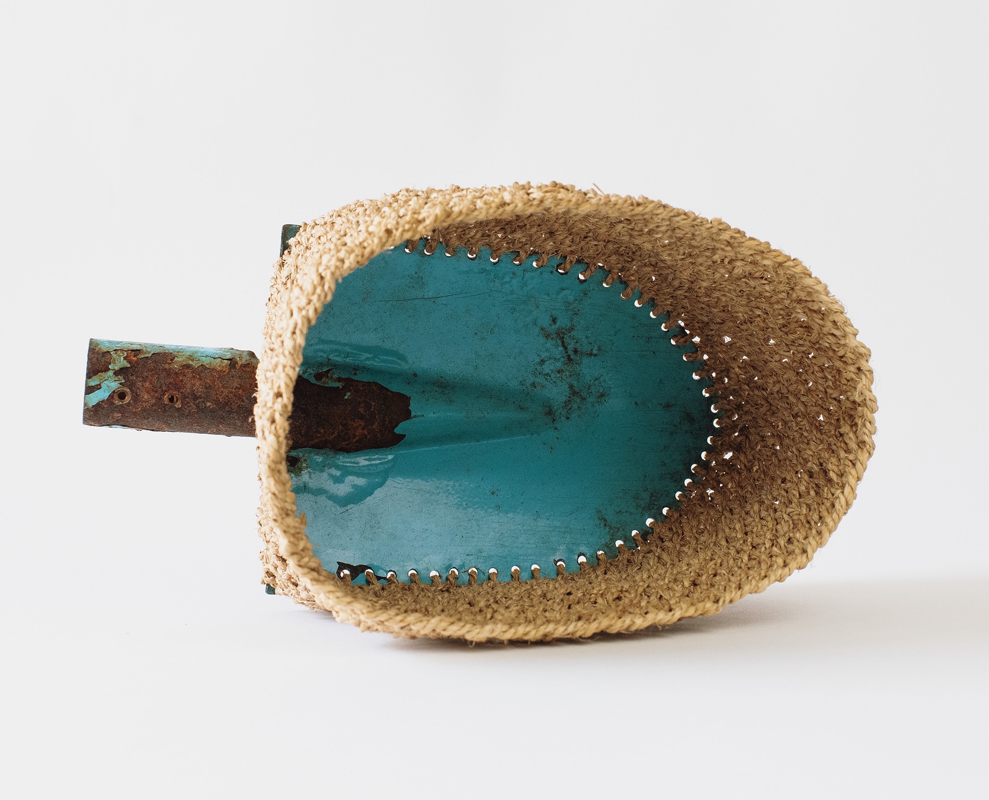 a garden spade on its side which has been woven around the edges to create a basket-type vessel