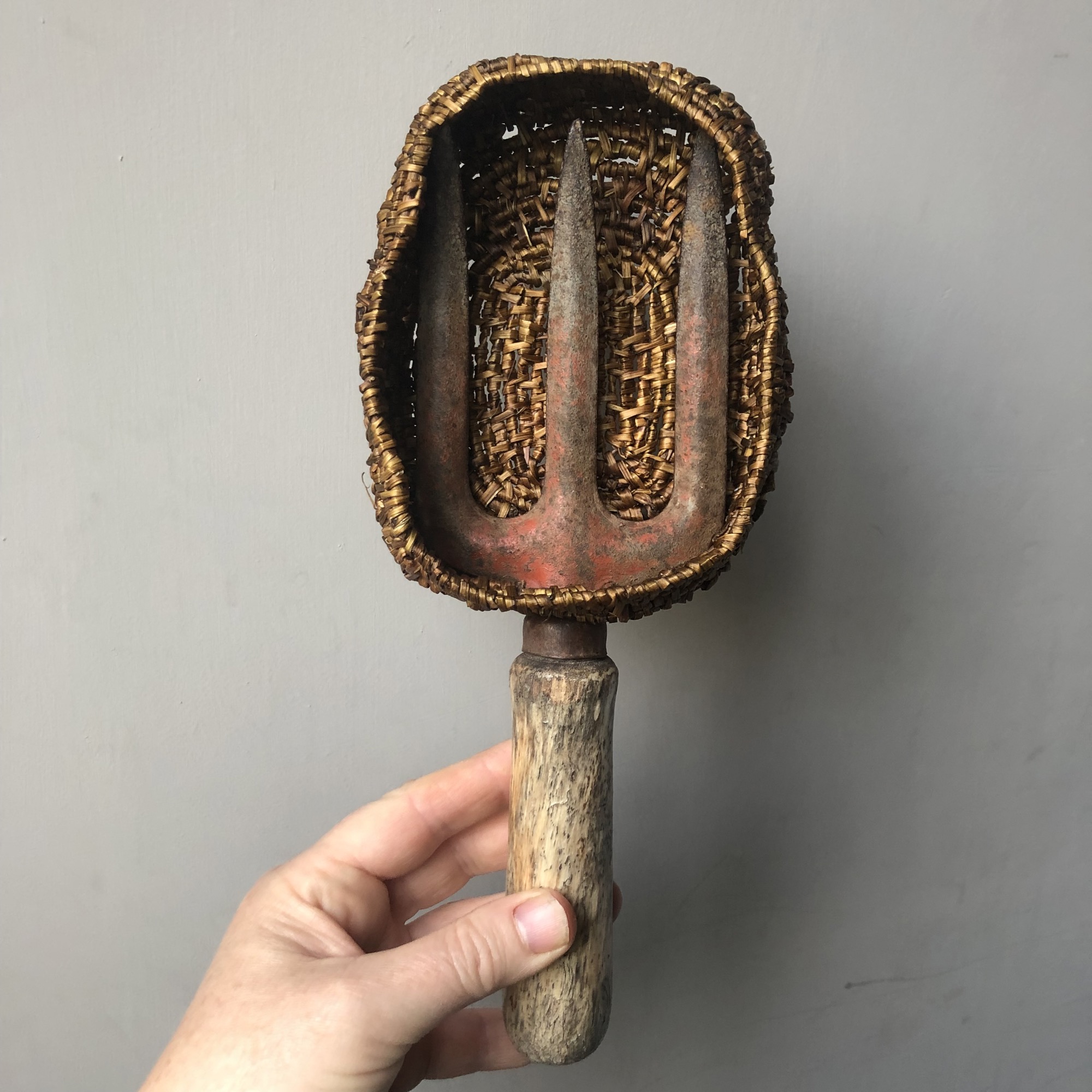 a garden fork with its tines wrapped in small handwoven basket