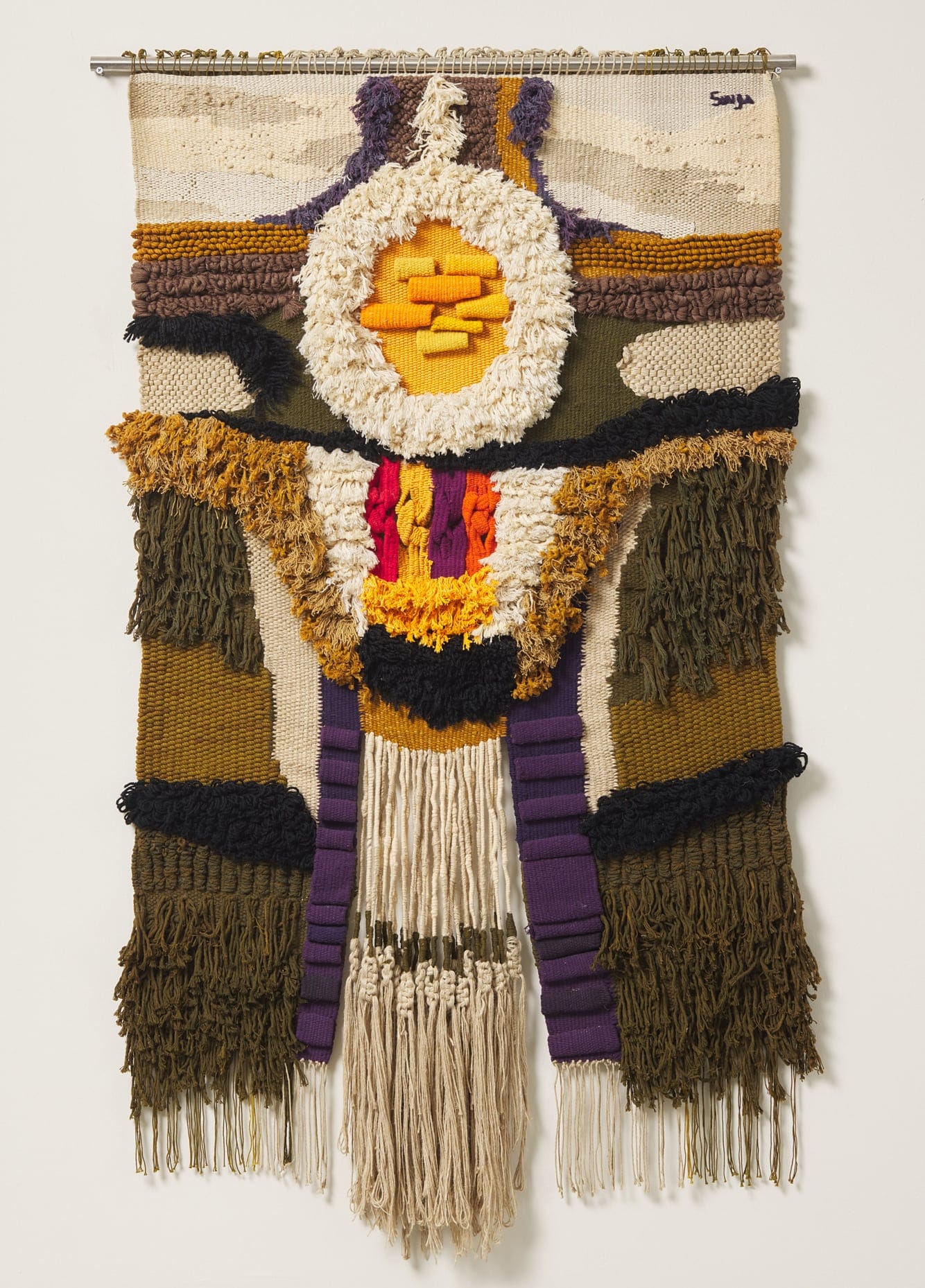 an abstract weaving with dangling threads, tufted portions, and flat weaves. threads are green, purple, yellow, and neutrals