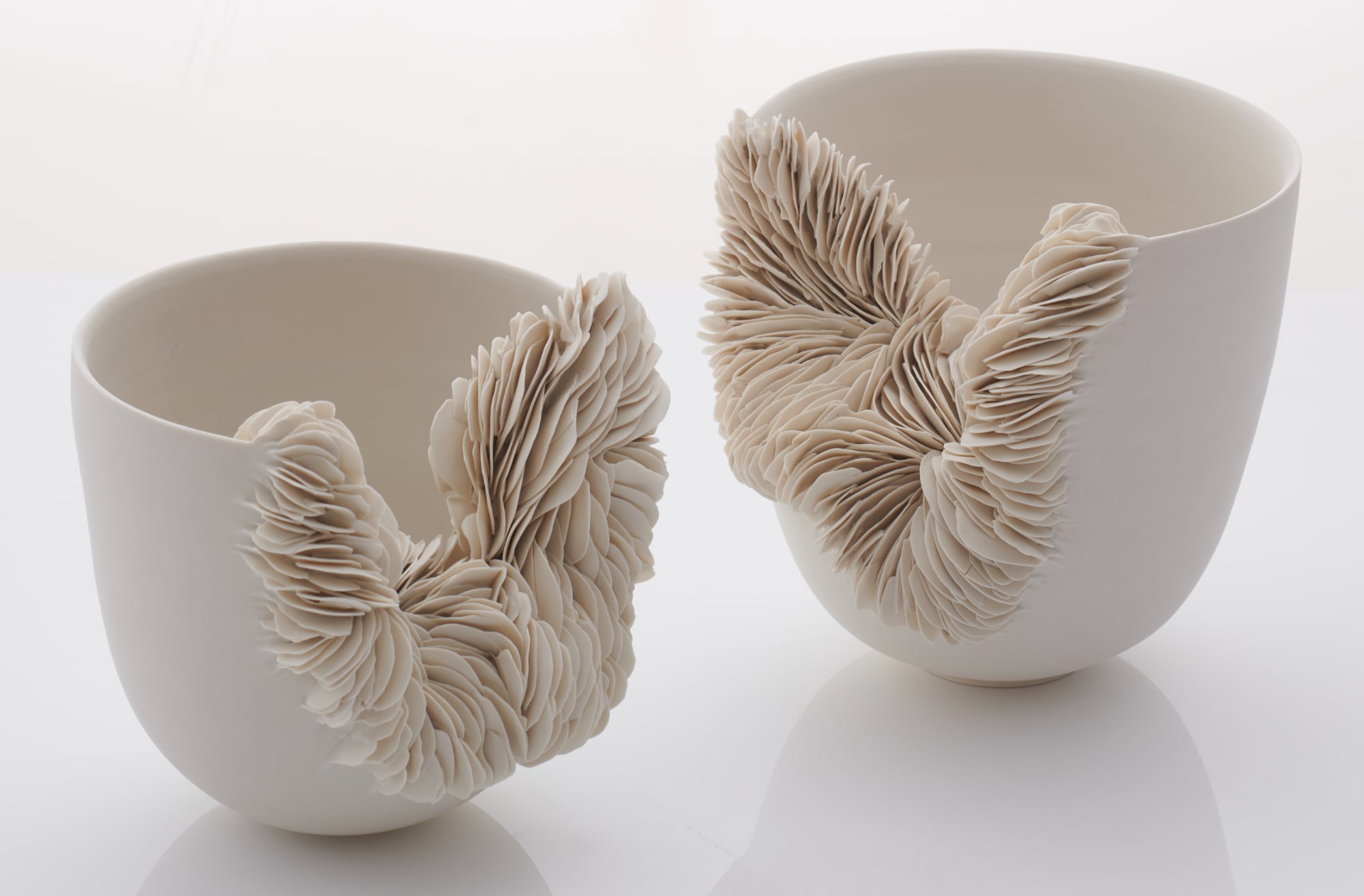 two white porcelain vessels that erupt into innumerable layered fragments