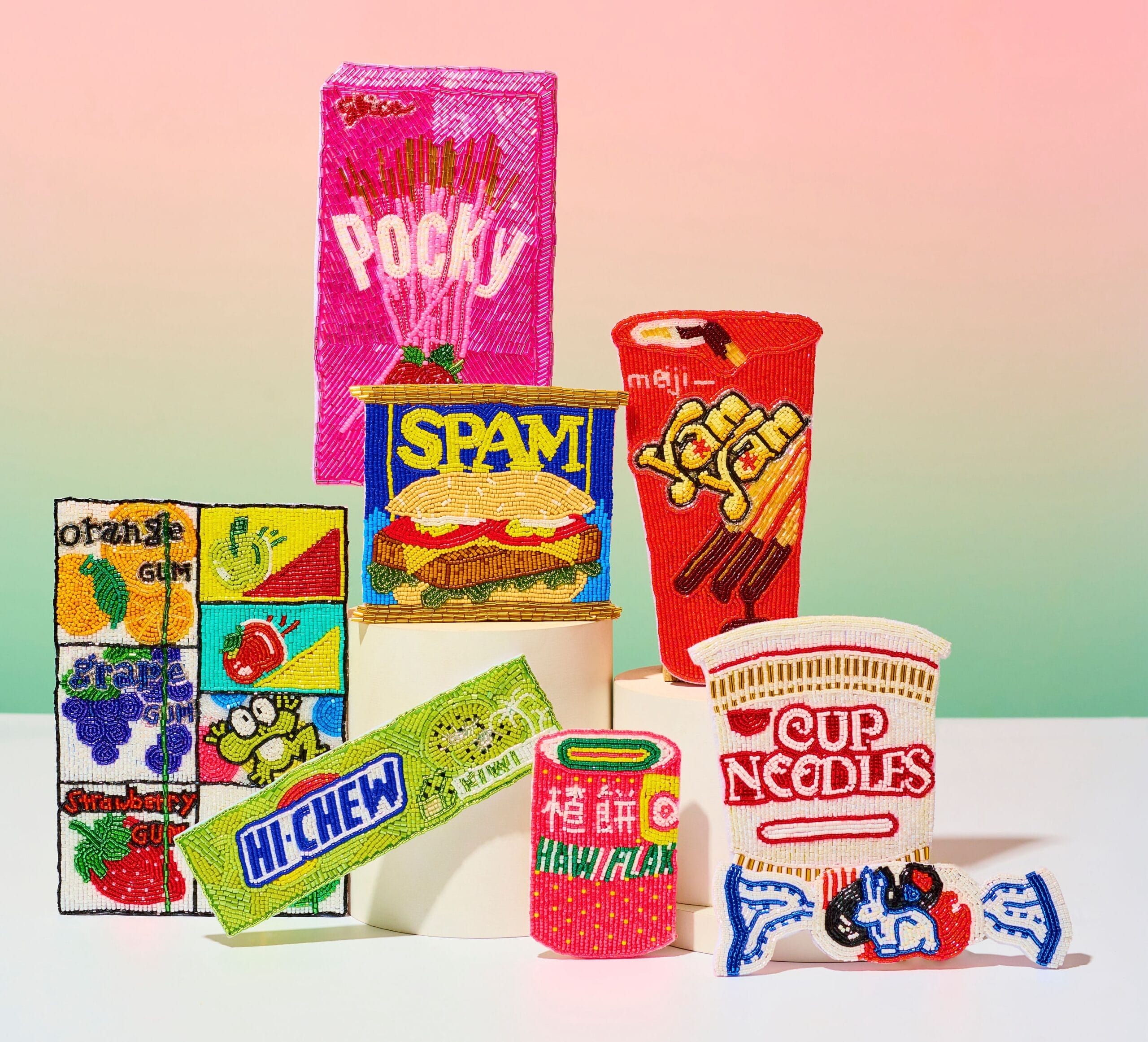 A display of several beaded depictions of treats and snacks such as strawberry Pocky, Yan-Yan, Spam, Cup Noodles, Hi-Chew, Botan Rice Candy, White Rabbit, and Murakawa Bubble Gum.