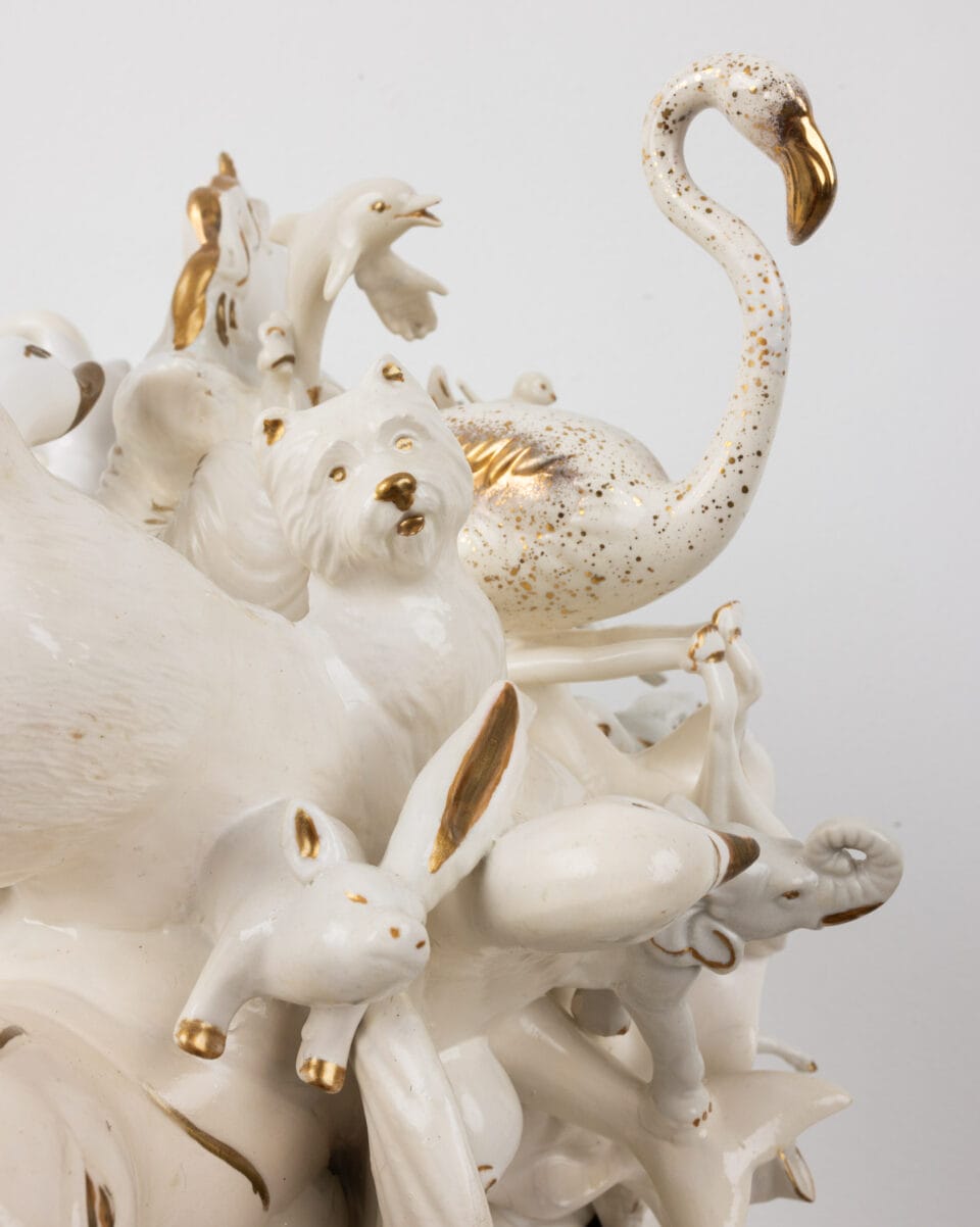 a detail of a sculpture made of small ceramic objects and animals assembled together into a white-and-gold grouping