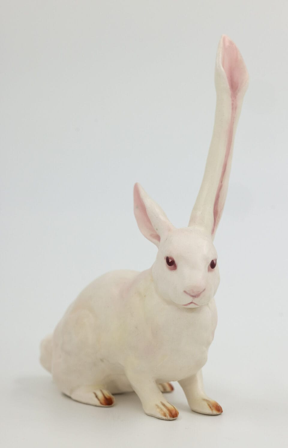 a reimagined secondhand ceramic kitsch piece of a white rabbit with one extra long ear