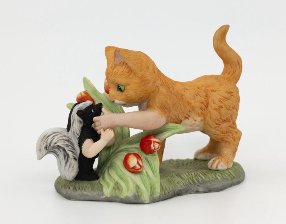 a reimagined secondhand ceramic kitsch piece of a cat and skunk with both animals given human arms