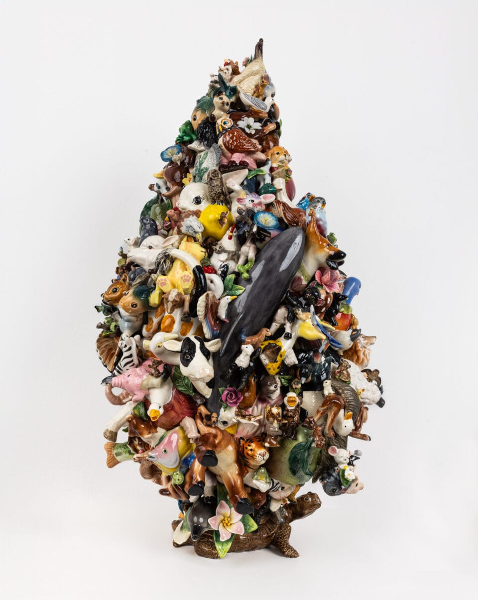 a sculpture of small ceramic objects and animals assembled together into a cone shape