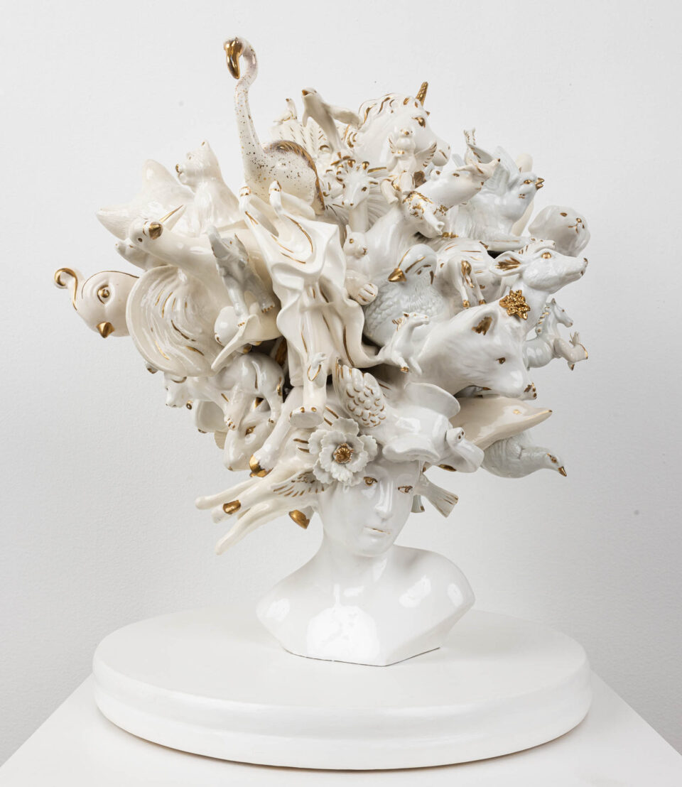 a sculpture made of small ceramic objects and animals assembled together into a white-and-gold grouping